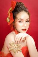 modelo de jovem mulher bonita asiática em um elegante vestido vermelho de luxo elegante sobre um fundo vermelho isolado.