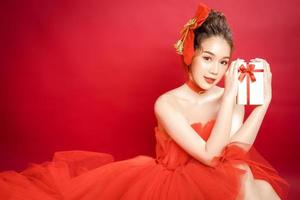 modelo de jovem mulher bonita asiática em um elegante vestido vermelho de luxo elegante sobre um fundo vermelho isolado. foto