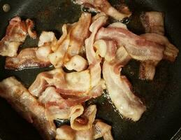 tiras de bacon cozinhando na frigideira ou frigideira foto