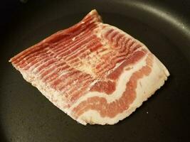 tiras de bacon cru congelado na frigideira ou frigideira foto