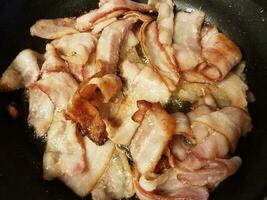 bacon cozinhando na frigideira ou frigideira no fogão foto