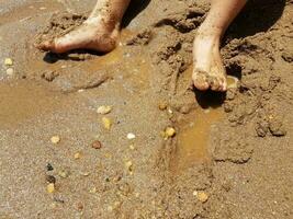 pés de criança na areia com pedras foto