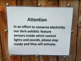 sinal de atenção de papel branco laminado sobre conservação de energia na cerca de madeira foto