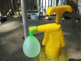 dispensador de água de plástico amarelo enchendo um balão de água verde foto