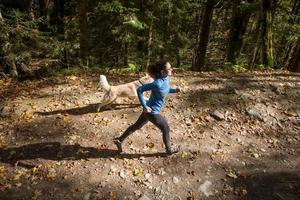 jovem corredor feminino treinando na floresta de outono com cachorro foto