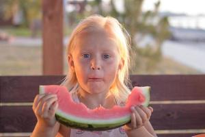 garota engraçada come fatias de melancia foto