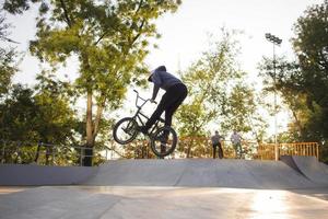 bmx rider treinando e fazendo truques na street plaza, bicyxle stunt rider em coccrete skatepark foto