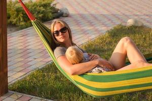 jovem mãe relaxante com a filha na rede na praia foto