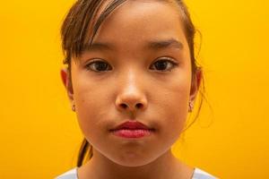 linda garota asiática sentada no fundo amarelo. menina asiática feliz sorrindo. foto