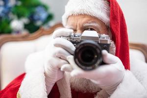 papai noel segurando a câmera vintage. retrato isolado em fundo amarelo. foto