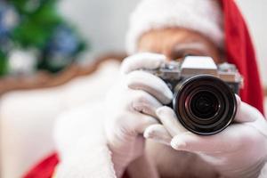 papai noel segurando a câmera vintage. retrato isolado em fundo amarelo. foto