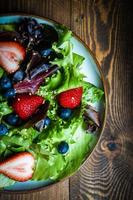 salada verde com frutas no fundo de madeira foto