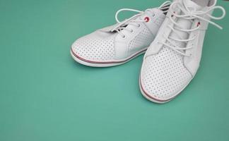 um par de sapatos brancos em um fundo verde menta. vista de cima. sapatos modernos para esportes, caminhadas, corridas. espaço livre para texto.