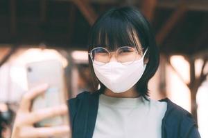 jovem mulher asiática adulta viajando usa máscara facial para proteger o vírus corona ou covid-19. foto