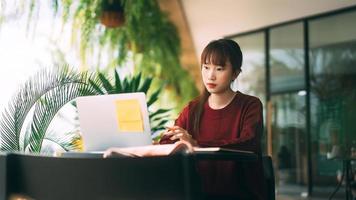 mulher jovem estudante universitário asiático adulto com laptop para estudar no café em dia de inverno.