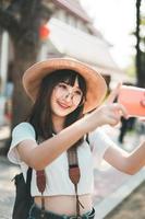 jovem garota de influência asiática viajando em bangkok com smartphone para upload na rede social. foto