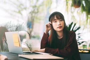 mulher jovem estudante universitário asiático adulto com laptop para estudar no café em dia de inverno. foto