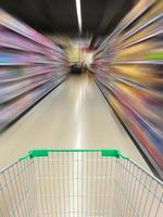 exibição de carrinho de compras de supermercado com desfoque de movimento do corredor do supermercado foto