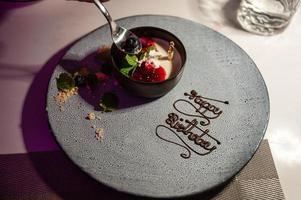 creme de baunilha com bolo de frutas na placa de cerâmica de feliz aniversário foto