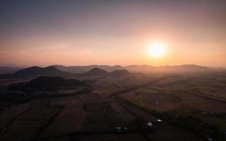 pôr do sol colorido sobre a montanha e campos de arroz colhidos em fazendas na zona rural foto