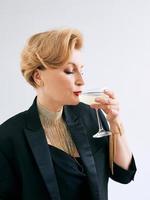 mulher elegante elegante madura de smoking com copo de vinho espumante. festa, celebração, conceito anti-idade foto