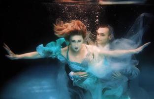 lindo casal dançando debaixo d'água na piscina foto