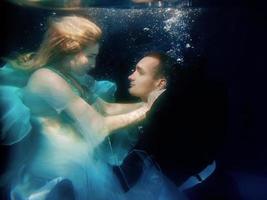 lindo casal dançando debaixo d'água na piscina foto