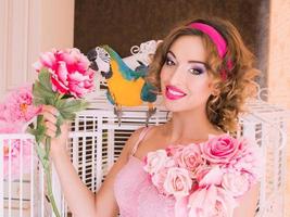 retrato de uma jovem mulher bonita em um vestido colorido com flores estilo boneca com ara no ombro foto