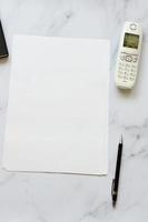 a4 papel em branco com telefone e óculos na mesa de escritório foto