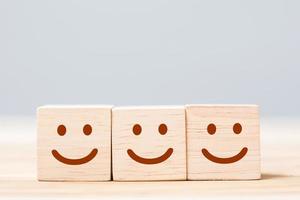 sorria o símbolo do rosto em blocos de cubo de madeira. emoção, classificação de serviço, classificação, avaliação do cliente, conceito de satisfação e feedback foto