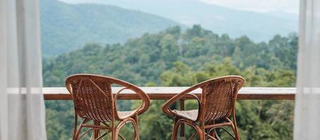 cadeiras de casal na varanda da casa de campo ou homestay com fundo de vista para a montanha pela manhã foto