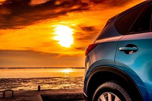 carro suv compacto azul com esporte e design moderno estacionado na estrada de concreto à beira-mar ao pôr do sol. tecnologia amiga do ambiente. conceito de sucesso empresarial. porta do carro suv azul com alça foto