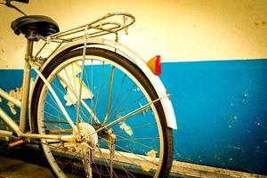 a bicicleta estacionada ao lado das velhas paredes de cimento pintadas de branco e azul. foto