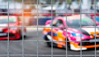 corridas de carros de automobilismo na estrada de asfalto. vista da rede de malha de vedação no carro turva no fundo da pista. super carro de corrida no circuito de rua. conceito de indústria automotiva. foto