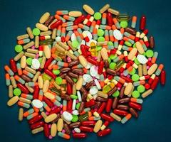 pilha de comprimidos coloridos e cápsulas pílulas sobre fundo azul. resistência a antibióticos e uso de drogas com conceito razoável. indústria farmacêutica. saúde mundial. conceito de interações medicamentosas foto