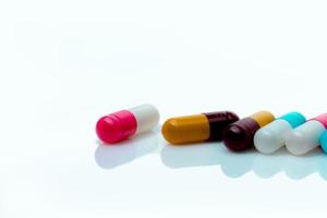 pílulas de cápsula antibiótica multicolorida em fundo branco. resistência a antibióticos. medicamentos prescritos. conceito de polifarmácia. produto de drogaria de farmácia. indústria farmacêutica. fabricação de cápsulas foto