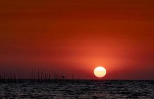 grande sol sobre o mar ao pôr do sol. lindo céu por do sol e horizonte. céu romântico vermelho para um fundo pacífico e tranquilo. fundo de inspiração e citação. beleza na natureza. cena de praia de verão. oceano. foto