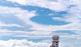 estação de cúpula de radar de observações meteorológicas contra o céu azul e nuvens fofas brancas. uso de torre de estação de observações meteorológicas aeronáuticas para aeronaves de segurança em negócios de aviação. torre esférica. foto
