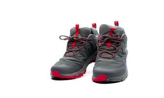 sapatos de trekking de homens isolados no fundo branco. sapatos de caminhada cinza-vermelho. calçado de segurança para escalada. equipamento de aventura. sapatos de trekking de borracha leve com sola de segurança. design moderno e respirável. foto