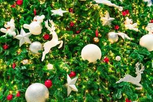 feche a decoração da árvore de natal com bolas vermelhas, douradas, prateadas e brancas, estrela de prata e renas brancas. fundo de natal. fundo de natal e feliz ano novo. bola colorida na árvore de natal. foto