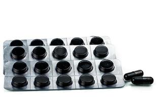 cápsulas e comprimidos comprimidos de carvão ativado em blister isolado no fundo branco foto