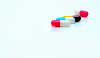 pílulas de cápsula antibiótica multicolorida em fundo branco. foco seletivo na pílula cápsula rosa e branca. resistência a antibióticos. medicamentos prescritos. indústria farmacêutica. drogas antimicrobianas. foto