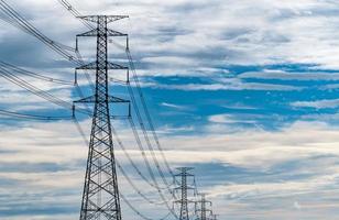 poste elétrico de alta tensão e fio elétrico com céu azul e nuvens brancas. poste de eletricidade alto. conceito de potência e energia. torre de grade de alta tensão com cabo de arame na estação de distribuição. foto