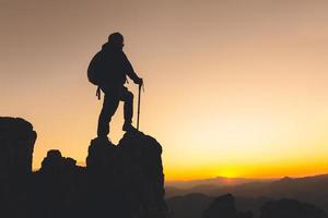 mulher de silhueta mochila viajar no topo de uma rocha alta, esportes e conceito de vida ativa, sucesso. foto