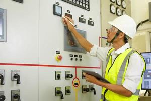 engenheiro que trabalha na subestação de distribuição de energia elétrica do painel de controle de status. informações de registro de eletricista e ferramenta na sala de comutação elétrica. foto