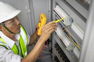 um eletricista masculino trabalha em um painel de controle com conexões elétricas conectando dispositivos com uma ferramenta de conceito de trabalho complexo. foto