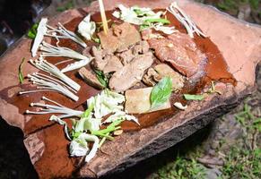 comida na pedra - carne de porco grelhada shabu shabu e legumes e cogumelos na placa de pedra quente, sobrevivência no conceito selvagem foto