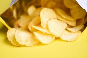 batatas fritas em fundo amarelo, batatas fritas é lanche no pacote de saco embrulhado em plástico pronto para comer e comida gorda ou junk food foto