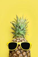 conceito de verão. abacaxi com óculos de sol amarelos e espaço para texto foto