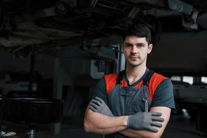 retrato de trabalhador sério de uniforme que fica em sua oficina com chave na mão foto